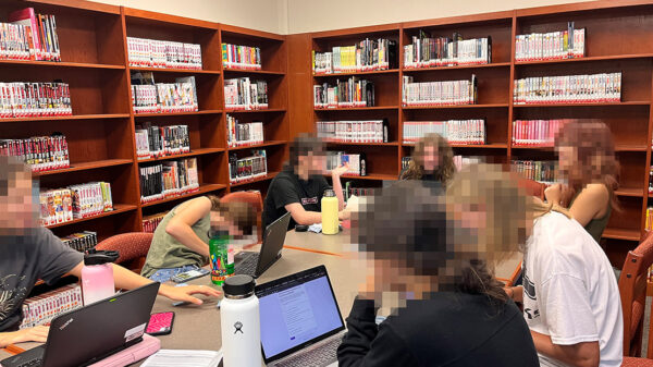 A group of students reading around a desk.