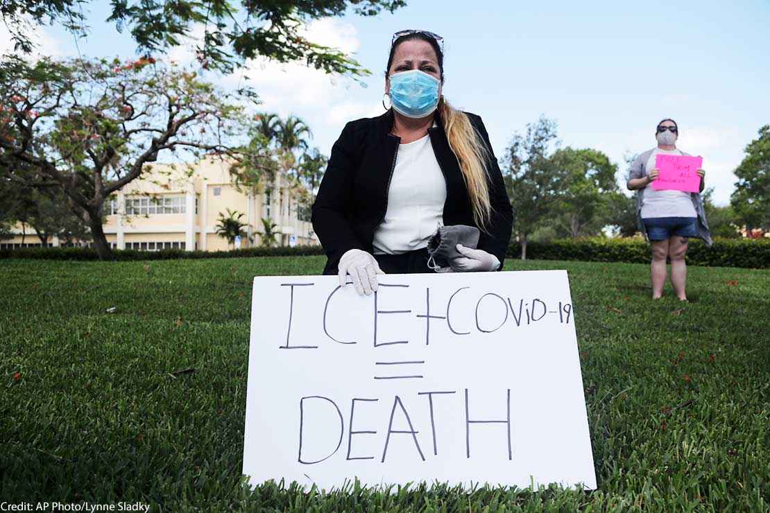 A woman wears a protective face mask and gloves as she protests outside of a U.S. Immigration and Customs Enforcement field office Friday, May 29, 2020, in Plantation, Fla.