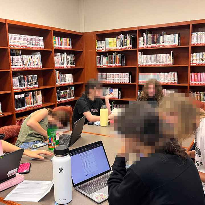 A group of students reading around a desk.